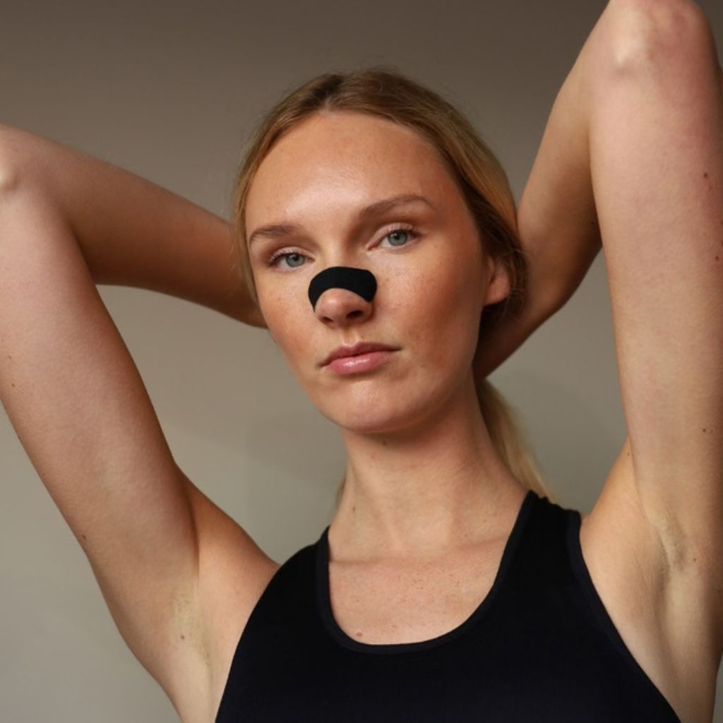 Vrouw in sporttopje met een zwarte neusstrip voor vrijere neusademhaling tijdens het sporten.