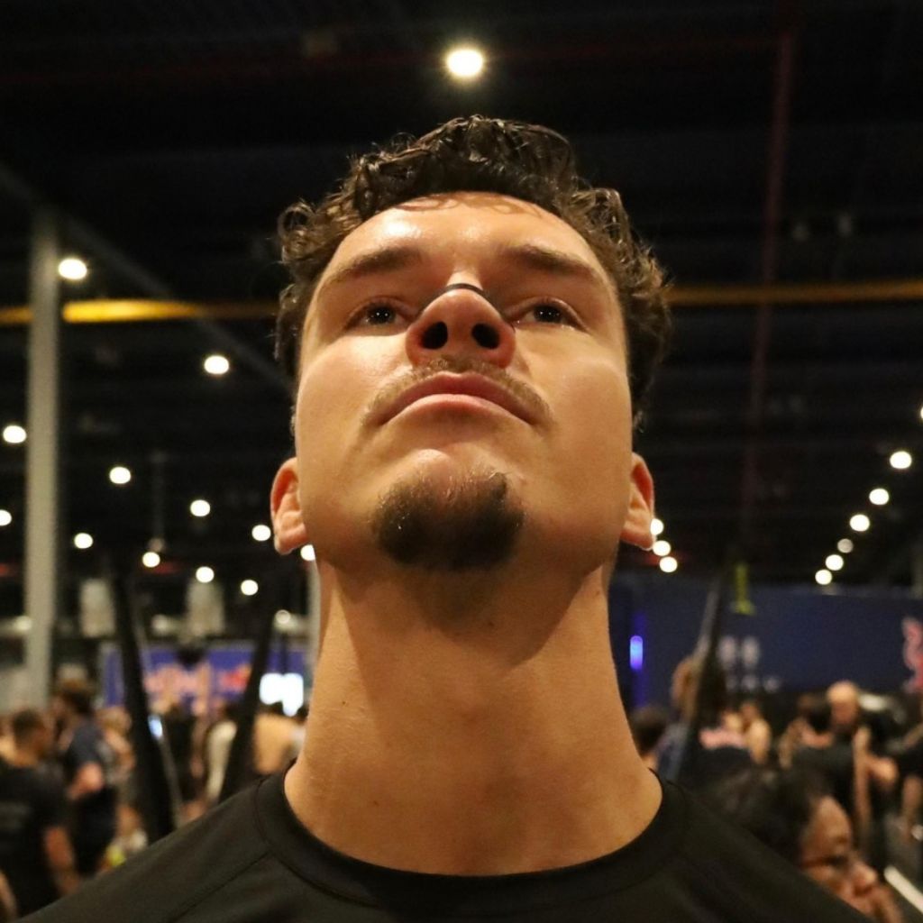 Atleet met een zwarte neusstrip kijkt omhoog in een wedstrijdhal tijdens hardlopen en functionele training.